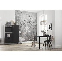 Lichte ruimte met keukentafel, stoel, kast met oven en wandbehang met bloemmotief.