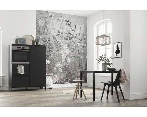 Lichte ruimte met keukentafel, stoel, kast met oven en wandbehang met bloemmotief.