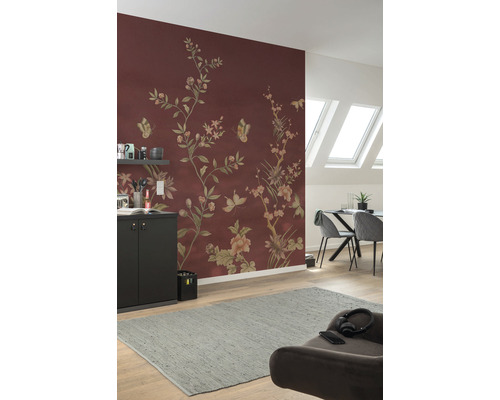 Woonkamer met bloemmotief behang in roodbruin, eettafel, stoelen en grijs tapijt.