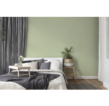 Slaapkamer met bed, nachtkastje en subtiel groen geschilderde muur