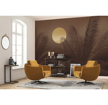 Woonkamer met palmbehang, twee fauteuils, plank en tapijt.