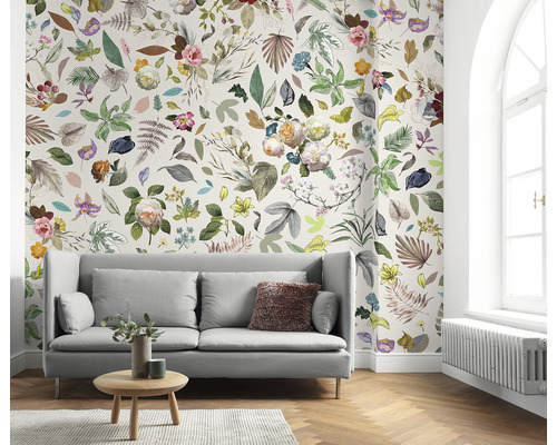 Woonkamer met bank en bloemenbehang met bladeren en bloemen.