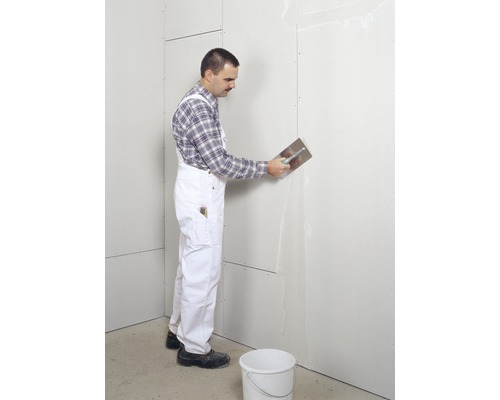 Vakman plamuurt gipsplaatwand met een plamuurmes