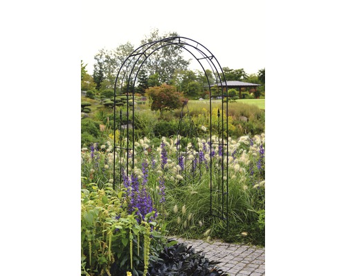 Tuinscene met metalen boog over een pad.