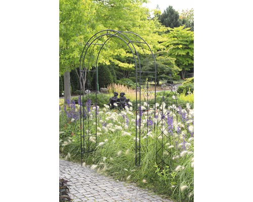 Tuinscene met rozenboog, siergrassen en een pad van straatstenen