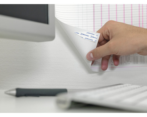 Een hand verwijdert een vel papier met plakstrips van een muur