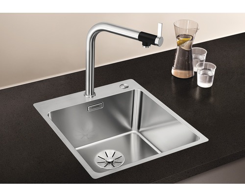 Roestvrijstalen spoelbak met kraan op donker aanrechtblad
