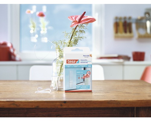 Tesa plakstrips verpakking op een houten tafel met haken en bloem