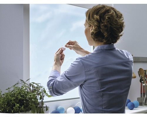 Vrouw bevestigt raamdecoratie aan het raam