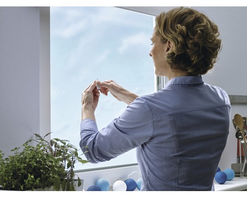 Vrouw bevestigt een raamfolie op het raam