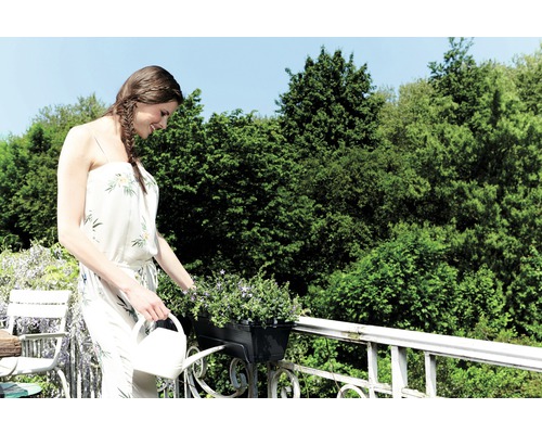 Vrouw geeft bloemen water op een balkon met een gieter