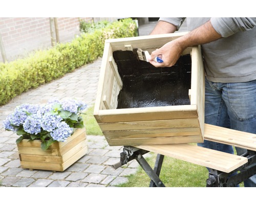 "Man schildert een houten plantenbak met een kwast