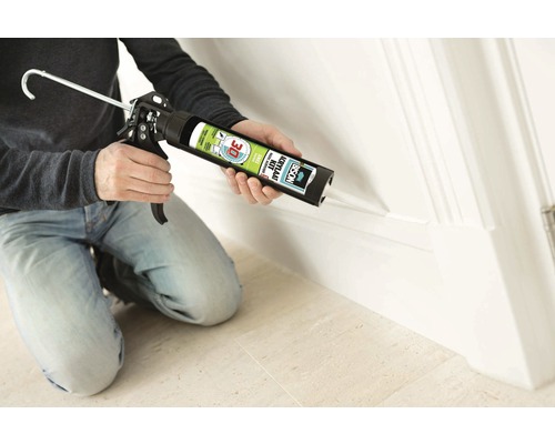 Ambachtsman gebruikt een kitspuit met acrylaatkit om een plint af te dichten.