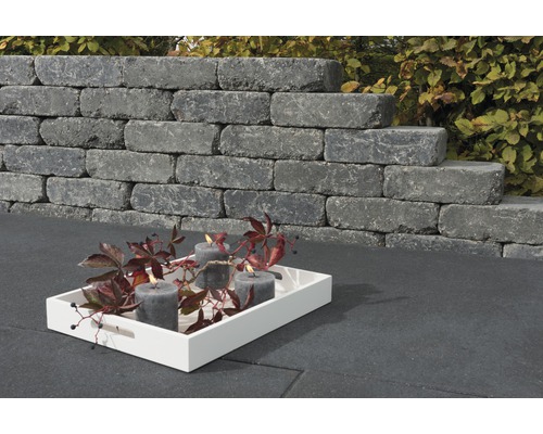 Gestapelde muurstenen met kaarsen op een dienblad in de tuin.