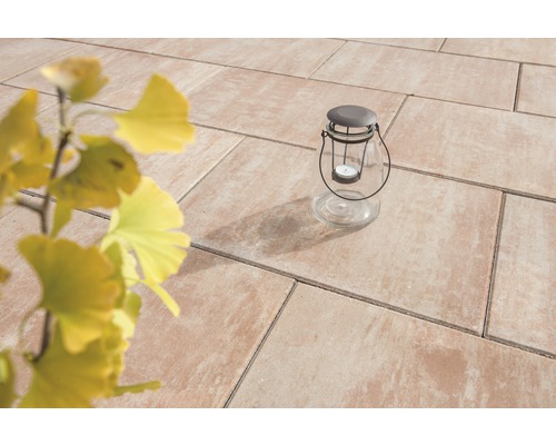 Tuinscene met terrastegels en glazen lantaarn met kaars