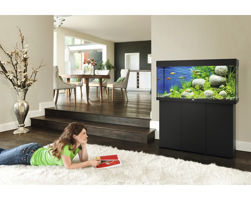Woonkamer met aquarium op onderkast en vrouw op tapijt