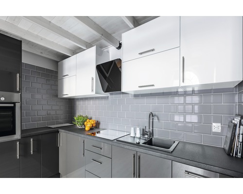 Moderne keuken met grijze tegels, witte en grijze kasten en een afzuigkap.