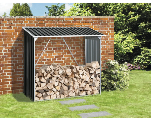 Metalen houtopslag met brandhout tegen een bakstenen muur