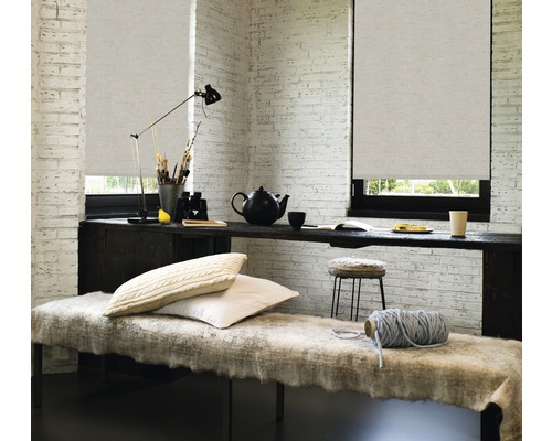 Inrichting met rolgordijnen voor ramen, tafel, bank en accessoires in een lichte kamer.