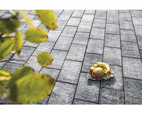 Grijze straatstenen met fruit op een schaal in de buitenlucht.