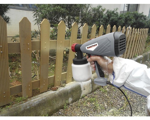 Verfspuitsysteem in gebruik bij het schilderen van een houten schutting