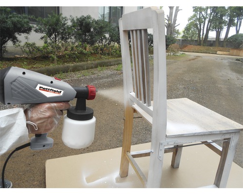 Verfspuitpistool dat een houten stoel bespuit