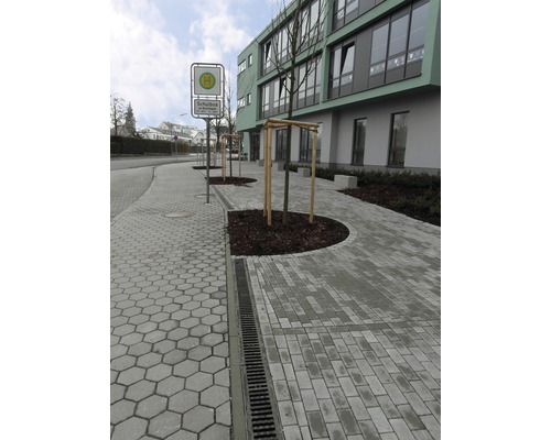 Buitenfoto van een bushalte met straatstenen en straatafwateringssysteem