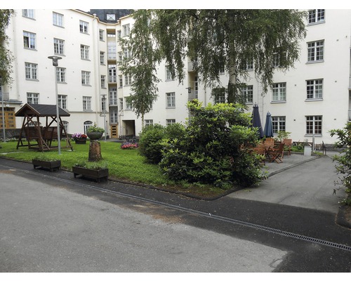 Binnenplaats met schommel, bloemperken, bomen en zitjes voor een gebouw met meerdere verdiepingen.