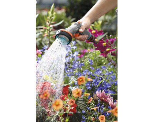 Een persoon besproeit bloemen met een Gardena tuinspuit.
