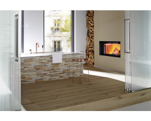 Badkamer met ligbad, open haard, stapel hout en houten vloer