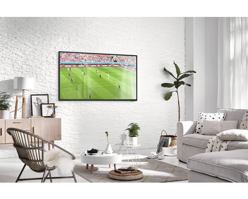 Lichte woonkamer met televisie, bank en fauteuil