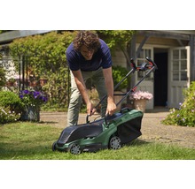 Een man gebruikt een Bosch grasmaaier in de tuin.