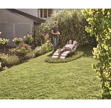 Vrouw ontspant op een tuinligstoel in de tuin, terwijl een man ernaast staat.