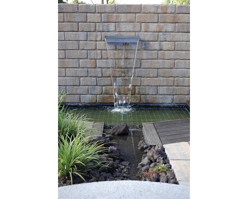 Tuin met waterval voor een stenen muur