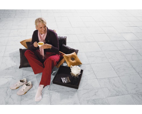 Vrouw zit met kop thee op de betegelde vloer