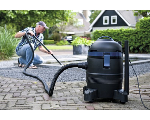 Vijverslibzuiger in gebruik buitenshuis voor het reinigen van tuinvijver en omgeving