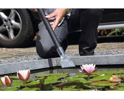 Persoon reinigt vijver met vijverstofzuiger in tuinvijver