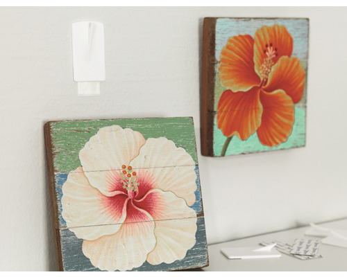 Twee houten afbeeldingen met bloemmotieven, bevestigd met een zelfklevende haak.