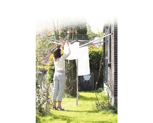 Vrouw hangt wasgoed te drogen op een waslijn in de tuin