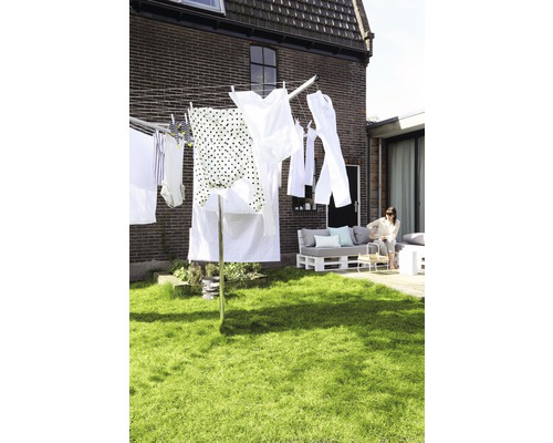 Droogmolen met wasgoed in de tuin voor bakstenen huis