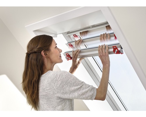 Vrouw bedient een dakraam met een verduisterend rolgordijn.