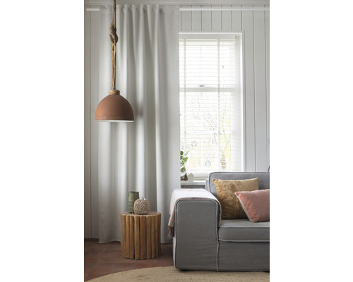 Woonkamer met gordijn, bank, bijzettafel en hanglamp voor een gezellige sfeer.