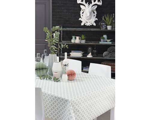 Decoratieve eettafel met tafelkleed, vazen en een plank op de achtergrond.