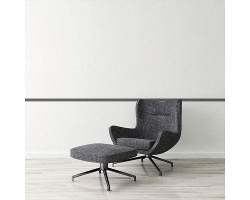 Fauteuil met voetenbank op houten vloer voor een witte muur