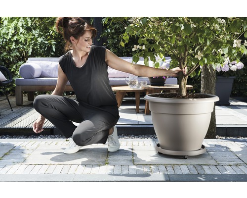 Vrouw hurkt naast een beplante bloempot in de tuin