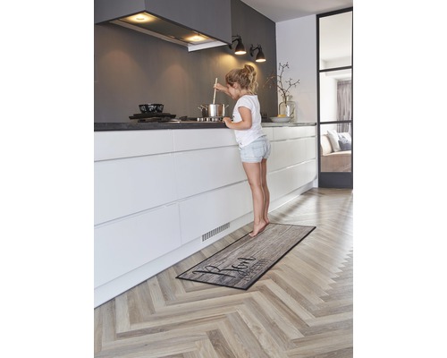 Keuken met keukenloper in houtdesign en jong meisje bij het fornuis