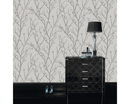 Behang met boomtakmotief in kamer met ladekast en lamp