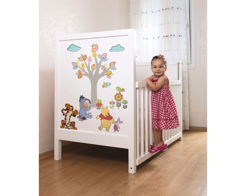 Wit kinderbed met Winnie de Poeh-motieven in een kinderkamer.