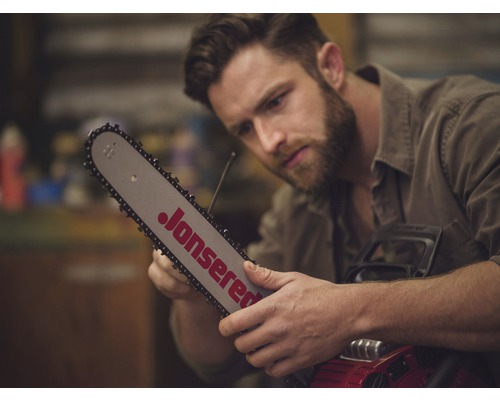 Een man inspecteert een Jonsered kettingzaag.