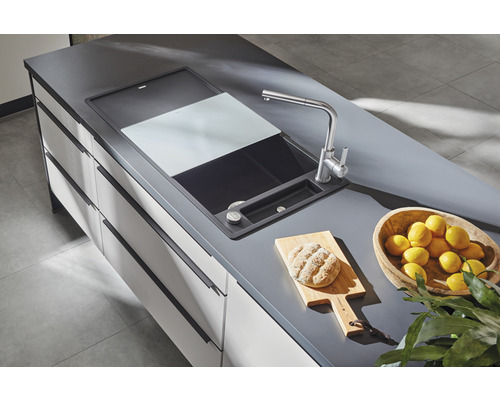 Spoelbak met snijplank, kraan, brood op snijplank en schaal met citroenen op een werkblad